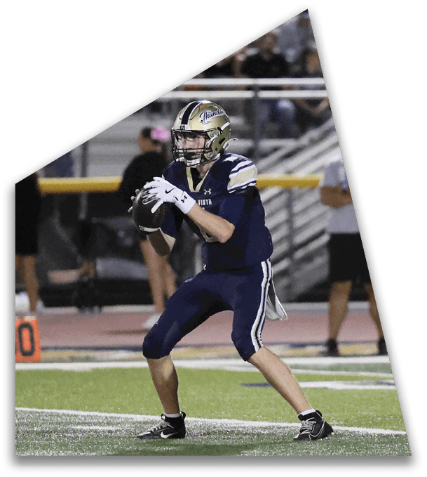 Two people in football uniforms are running on a field with one person in a helmet and pads chasing the other. Description generated by AI