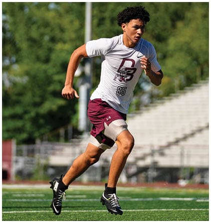 A football player wearing a blue and red jersey. Description generated by AI