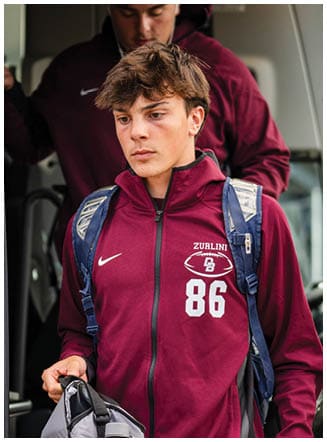 A football player wearing a blue and red jersey. Description generated by AI