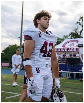A football player wearing a blue and red jersey. Description generated by AI
