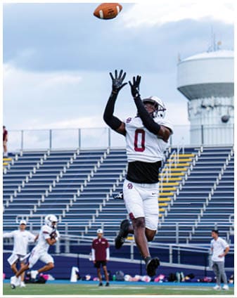 A football player wearing a blue and red jersey. Description generated by AI