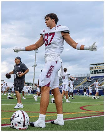 A football player wearing a blue and red jersey. Description generated by AI