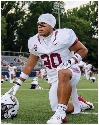 A football player wearing a blue and red jersey. Description generated by AI