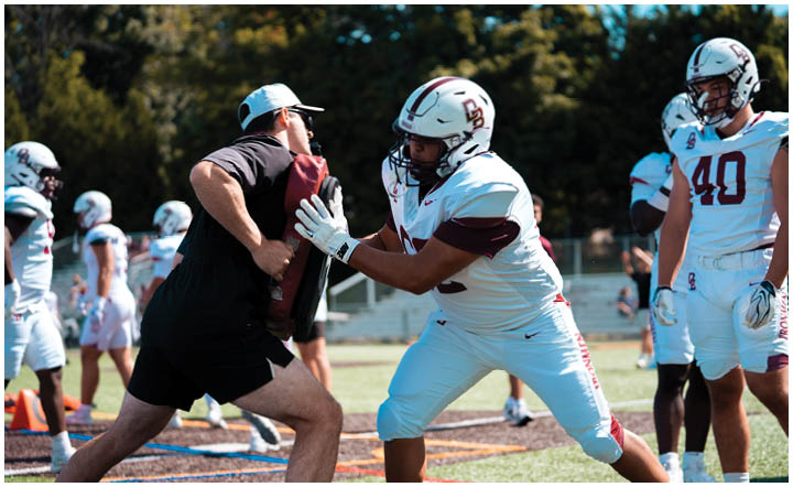 A football player wearing a blue and red jersey. Description generated by AI