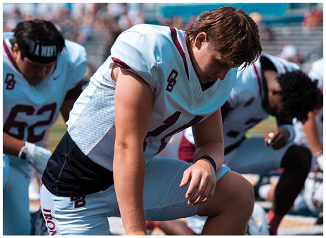 A football player wearing a blue and red jersey. Description generated by AI