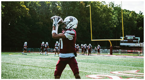 A football player wearing a blue and red jersey. Description generated by AI
