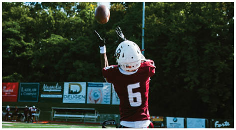 A football player wearing a blue and red jersey. Description generated by AI