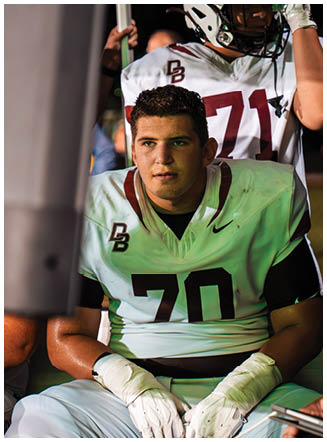 A football player wearing a blue and red jersey. Description generated by AI