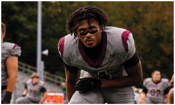 A football player wearing a blue and red jersey. Description generated by AI