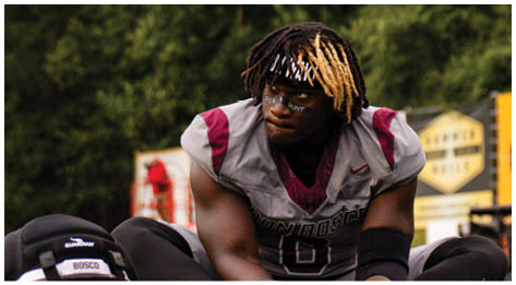 A football player wearing a blue and red jersey. Description generated by AI