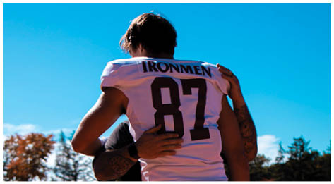 A football player wearing a blue and red jersey. Description generated by AI