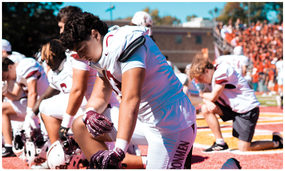 A football player wearing a blue and red jersey. Description generated by AI