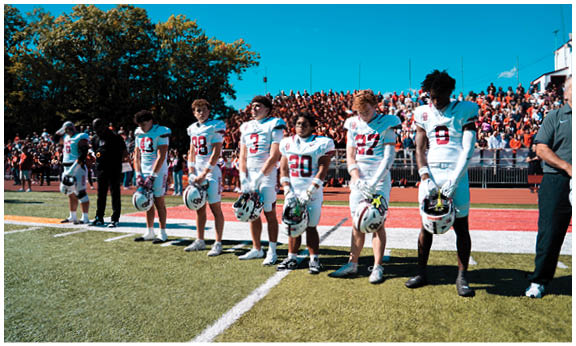 A football player wearing a blue and red jersey. Description generated by AI