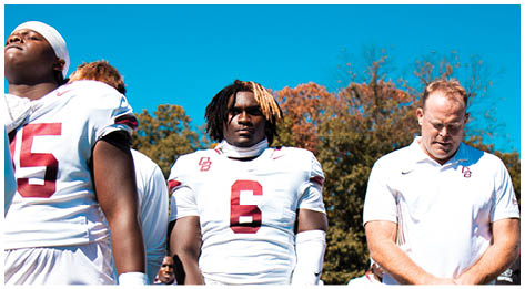 A football player wearing a blue and red jersey. Description generated by AI