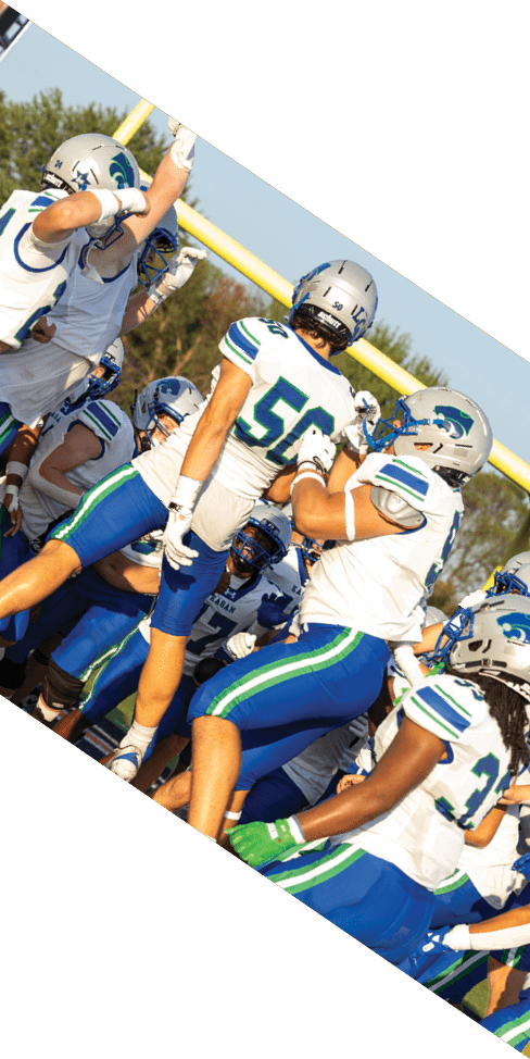 Two men are jumping in the air on a field, both wearing football uniforms. AI generated content