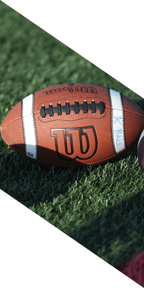 Two men are jumping in the air on a field, both wearing football uniforms. AI generated content