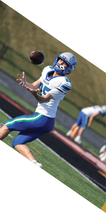 Two football players are on the field, one jumping in the air while the other is running. A referee is also present, watching the play. AI generated content