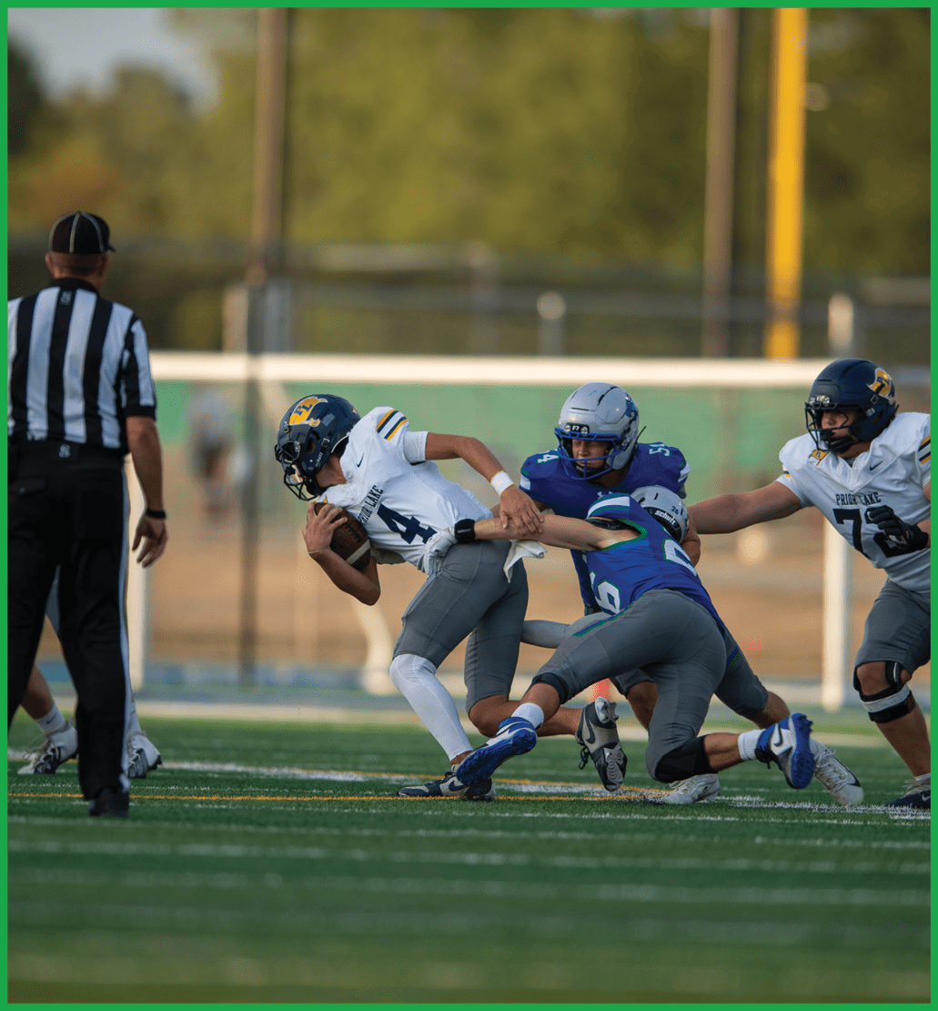 A football player in a green jersey is running with the ball. Description generated by AI