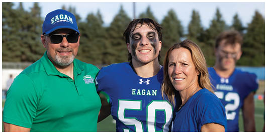 Three football players in blue and white uniforms running on a field. Description generated by AI