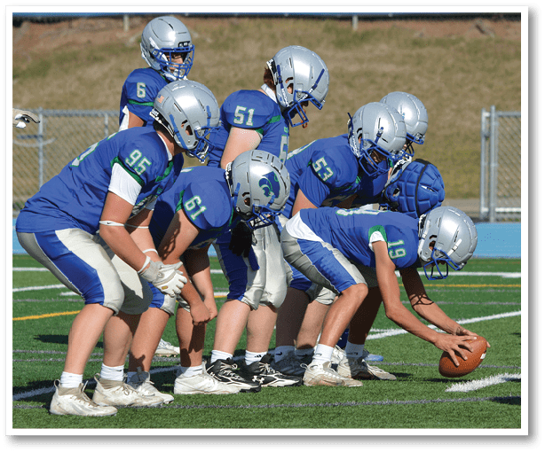 A group of people playing football on a field. Description generated by AI