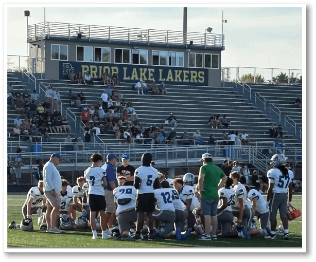A group of people playing football on a field. Description generated by AI