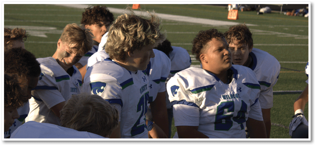 A group of football players on a field. Description generated by AI
