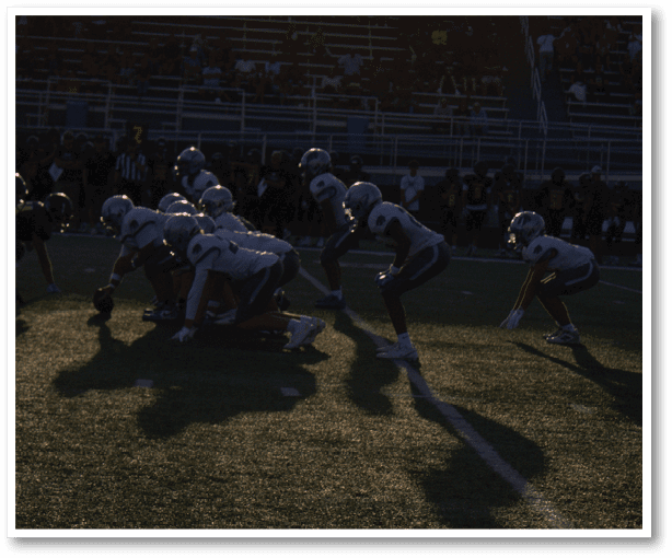 A group of people playing football on a field. Description generated by AI