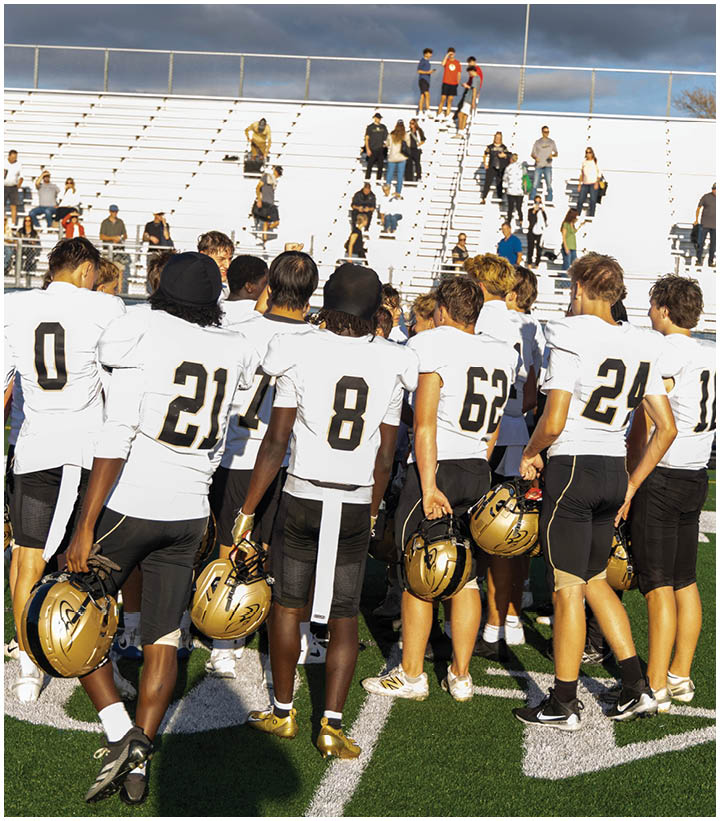 A group of football players wearing black and white uniforms. Description generated by AI