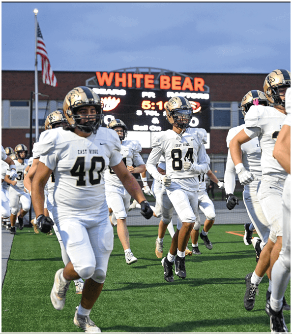 A group of football players wearing black and white uniforms. Description generated by AI