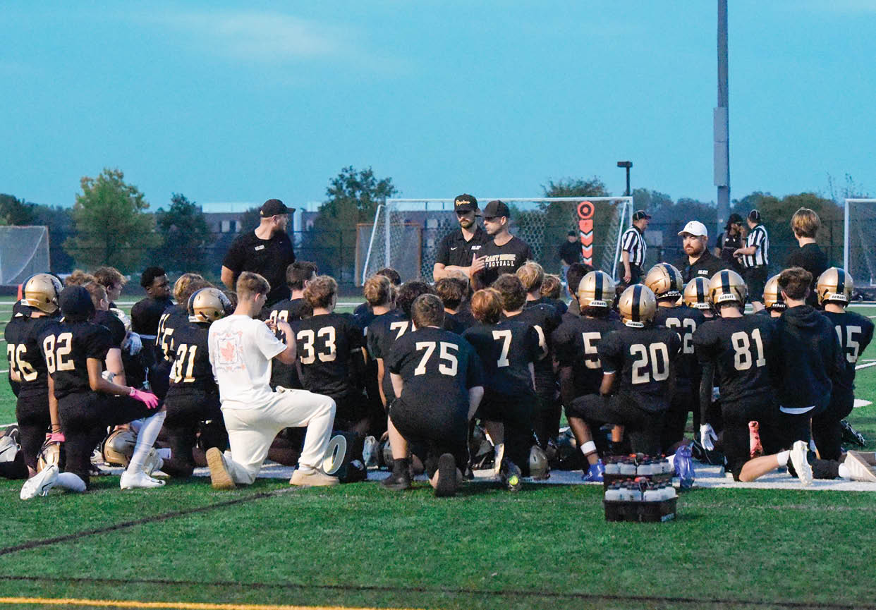 A group of football players wearing black and white uniforms. Description generated by AI