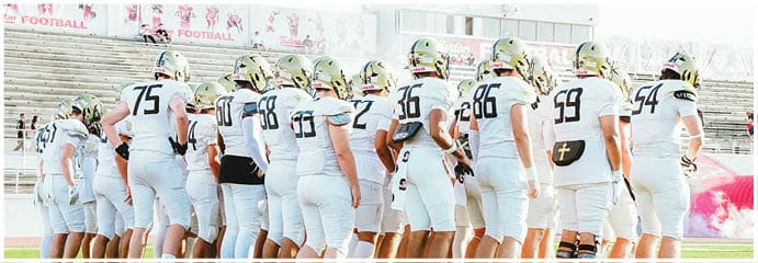 A football game is taking place on a field with players wearing blue and white uniforms. Description generated by AI