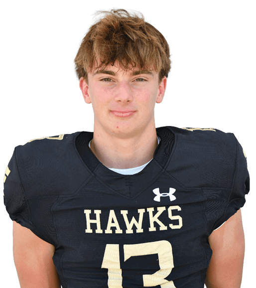 Person with curly hair wearing a black football jersey with the word “HAWKS" and the number 38 standing against a gray background. Description generated by AI