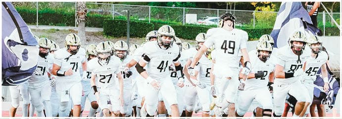 A football game is taking place on a field with players wearing blue and white uniforms. Description generated by AI