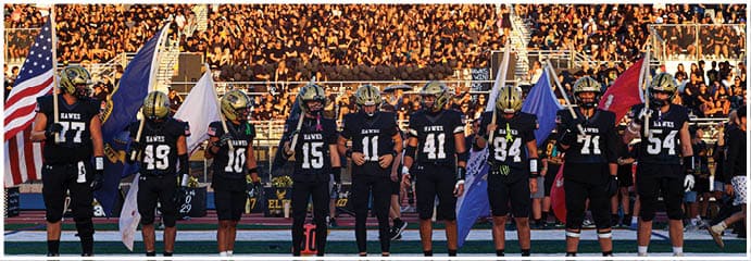 A football game is taking place on a field with players wearing blue and white uniforms. Description generated by AI