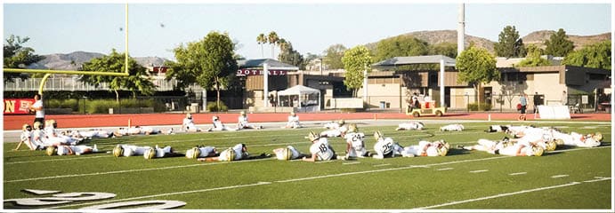 A football game is taking place on a field with players wearing blue and white uniforms. Description generated by AI