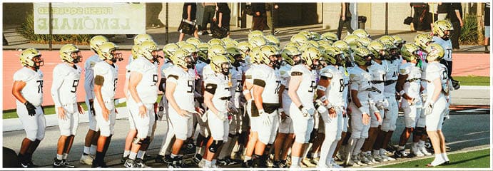 A football game is taking place on a field with players wearing blue and white uniforms. Description generated by AI