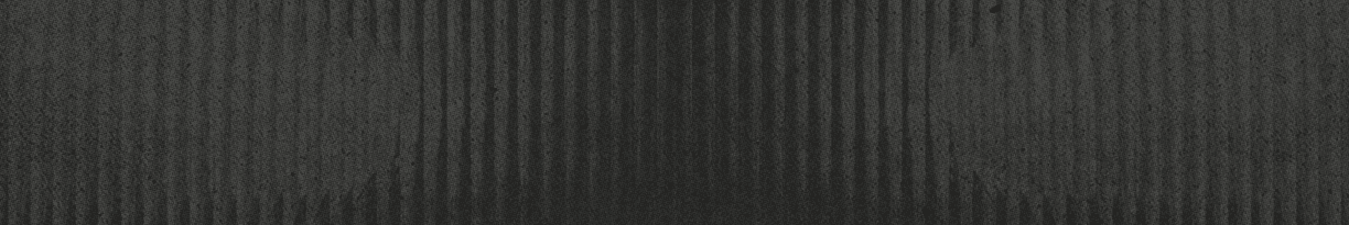 A textured dark surface with vertical ridges and subtle variations in shading. Description generated by AI