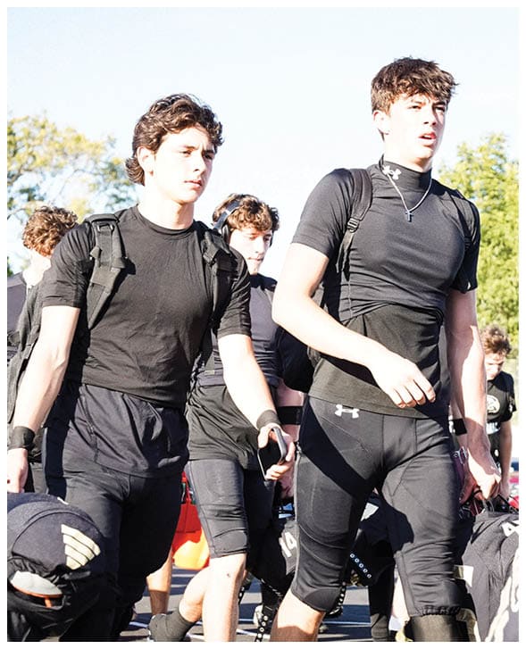 A group of football players wearing black jerseys with the number 3 on them. Description generated by AI