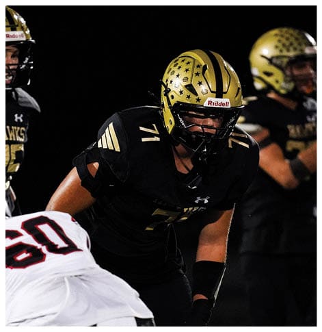 A football player wearing a black jersey with the number 6 on it. Description generated by AI