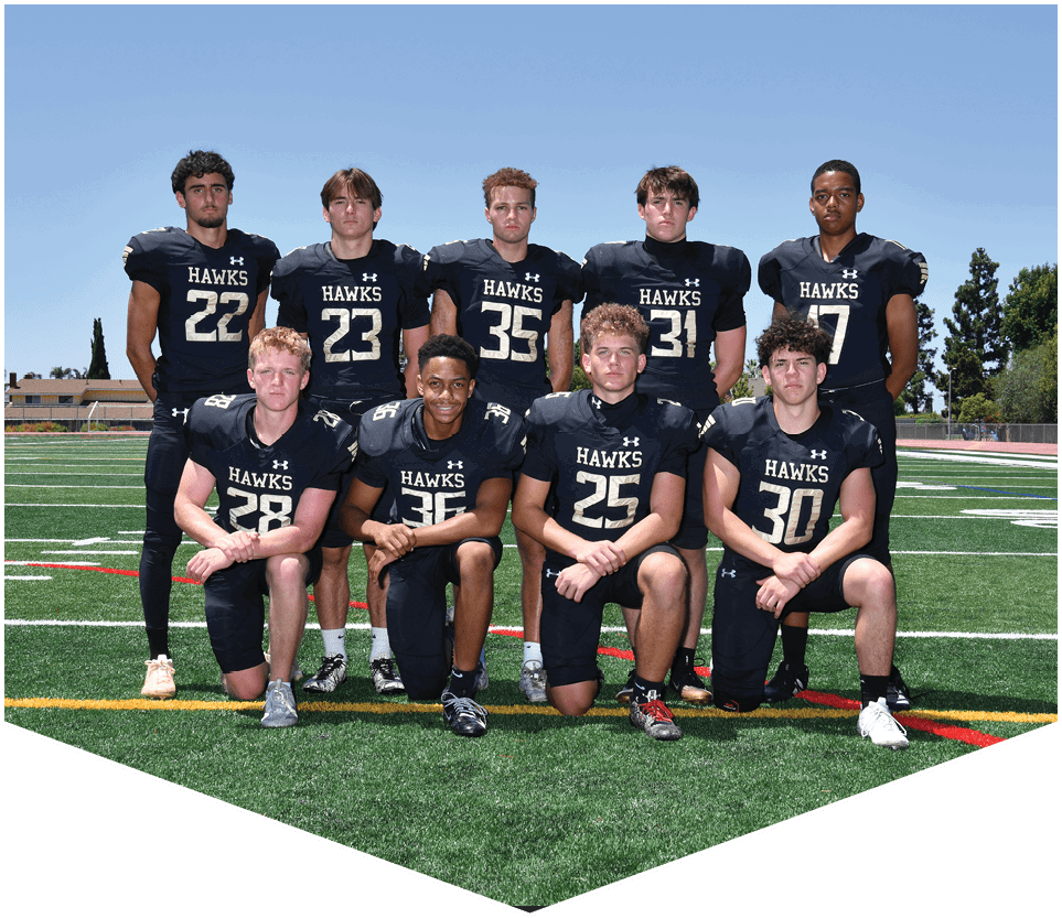 Nine people wearing black football uniforms with the word “HAWKS" pose on a green football field under a clear blue sky. Description generated by AI