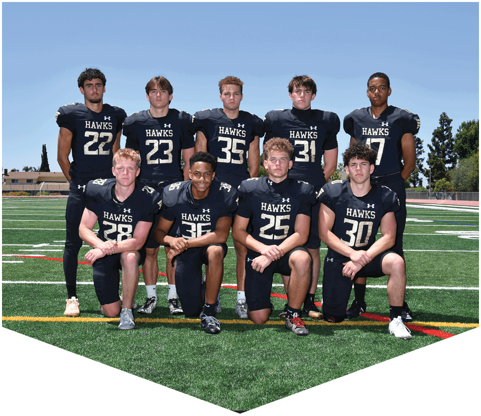 Nine people wearing black football uniforms with the word “HAWKS" pose on a green football field under a clear blue sky. Description generated by AI