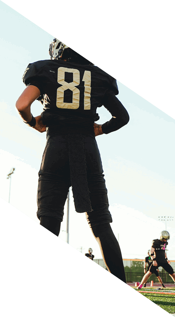 A football player wearing a black helmet and white jersey is holding a football in his hands. AI generated content