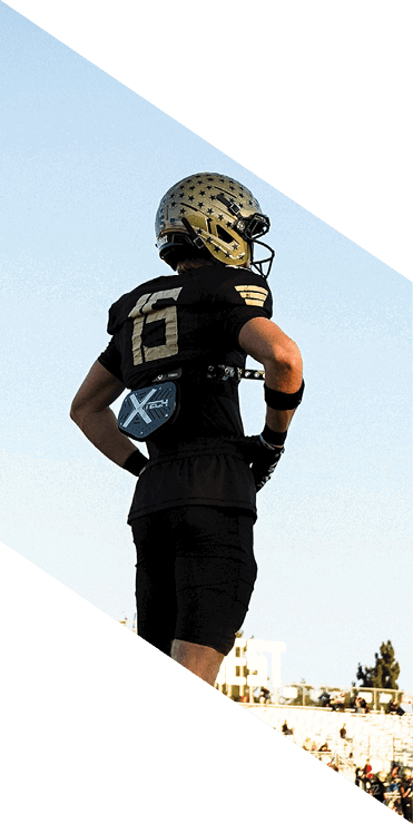 Two football players are on the field, one jumping in the air while the other is running. A referee is also present, watching the play. AI generated content