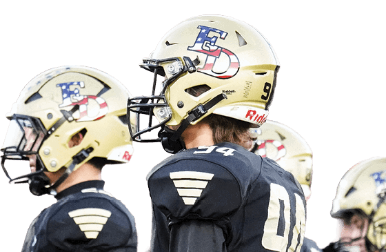 A group of people wearing black football uniforms and gold helmets are standing together on a field during a game. Description generated by AI