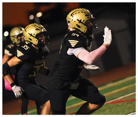 A football player wearing a black jersey with the number 6 on it. Description generated by AI