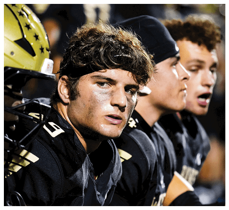 A football player wearing a black jersey with the number 6 on it. Description generated by AI