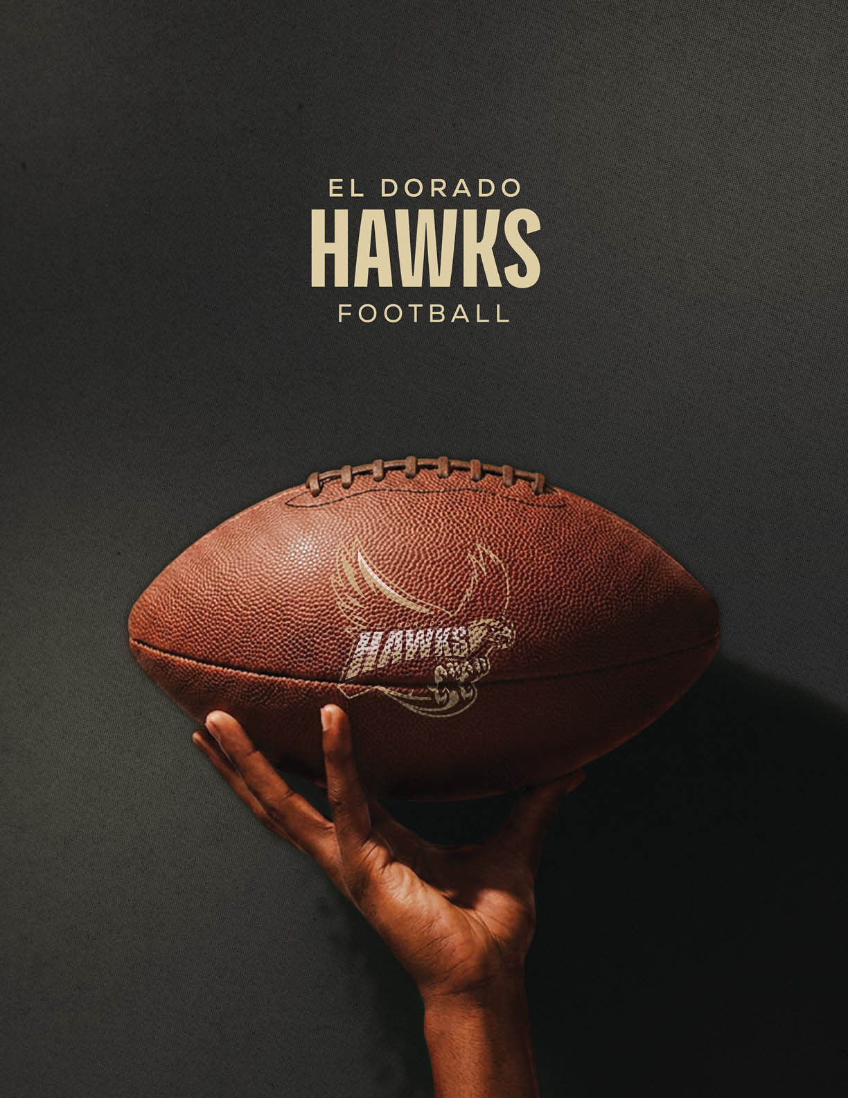 A hand is holding a football with the logo and text “El Dorado Hawks Football" on a dark background. Description generated by AI