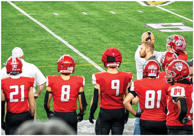 A group of football players wearing black and white uniforms. Description generated by AI