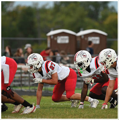 A football game is taking place with a group of men on the field. Description generated by AI