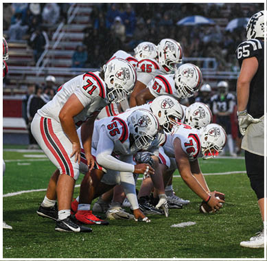 A football game is taking place with a group of men on the field. Description generated by AI